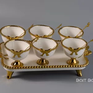 Gold dessert bowl set with six small cups and tray on grey background