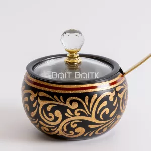 "Black sugar jar with gold ornamental patterns, red accent line, crystal knob, and gold spoon — luxurious decorative jar from Bait Baitk."
