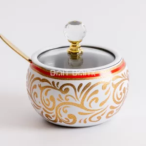 "White sugar jar with golden Arabic calligraphy and geometric designs, crystal knob, and gold spoon — luxurious Arabic-style serving jar from Bait Baitk."