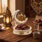 Crescent date dish filled with dates on an iftar table with a lantern